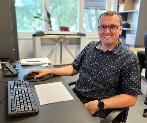 Ing. Pavel Ulbrich, technický ředitel AS Parking, zajišťující realizace, technický vývoj a zdokonalování řešení, sedí za černým kancelářským stolem s počítačovou sestavou, v dobré náladě a usmívá se do objektivu